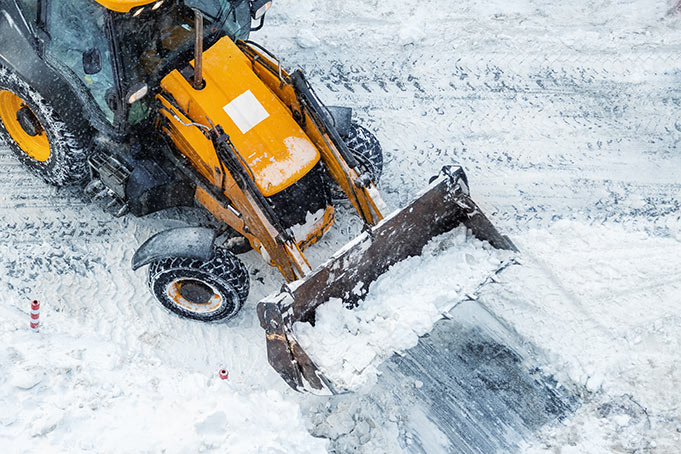 Tractor removing snow from parking lot Snow Removal and De-Icing Services